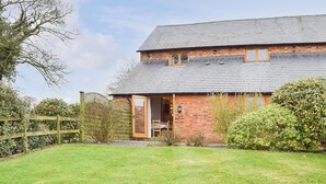 A two-story brick house with a sloped roof, a wooden door, and a small window. - The Old Dairy - UKC4698 (Kenilworth)