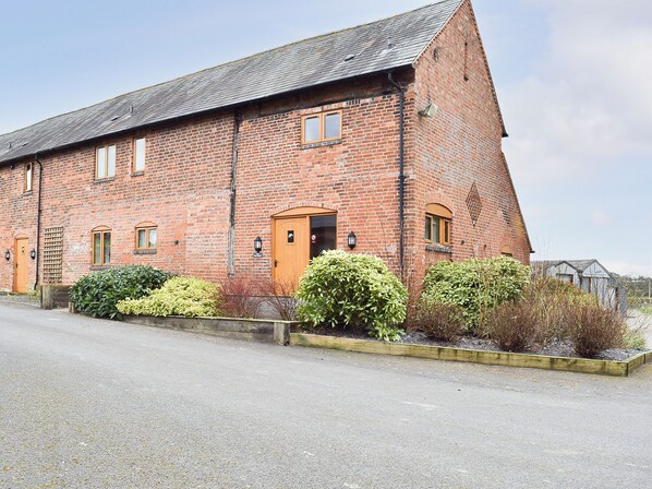 A large brick building with a sloped roof, a wooden door, and multiple windows. - The Old Dairy - UKC4698 (Kenilworth)