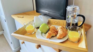 Een ontbijfwagen met croissants, een groene appel, sinaasappelsap en een koffiezetapparaat.