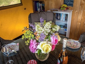 Une table à manger agrémentée d’un centre de table floral, une bouteille de vin et un menu.