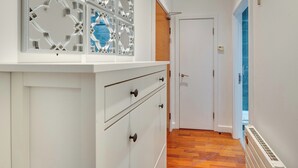 Un couloir avec une armoire blanche, une porte et un radiateur.