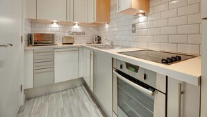 Une cuisine moderne avec des armoires blanches, un four encastré, une plaque de cuisson et un four à micro-ondes.