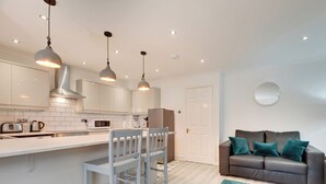 Een moderne keuken met witte kasten, een centraal eiland met barstoelen en hanglampen.