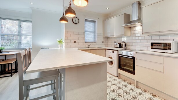 Een moderne keuken met een centraal eiland, inbouwapparatuur en hanglampen.