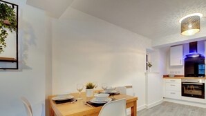 Una cocina moderna con armarios blancos, una mesa de comedor de madera y un horno empotrado.