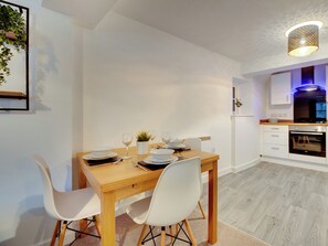 A modern kitchen with white cabinets, a wooden dining table, and a built-in oven. - 2 bedroom accommodation in Newcastle Upon Tyne (Newcastle Upon Tyne)