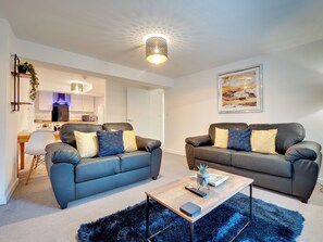 A modern living room with two sofas, a coffee table, and a kitchen in the background. - 2 bedroom accommodation in Newcastle Upon Tyne (Newcastle Upon Tyne)