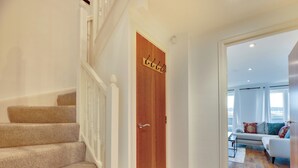 A staircase leading to a wooden door with a nameplate, a living room with a sofa and a view of the outdoors. - 2 bedroom accommodation in Newcastle Upon Tyne (Newcastle Upon Tyne)