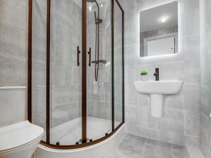 Ein modernes Badezimmer mit einer Duschkabine aus Glas, einem weißen Waschbecken und einer Toilette.