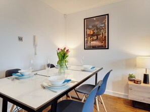 A dining area with a table set for two, chairs, a vase with flowers, a framed picture on the wall, and a lamp on the side table. - 2 bedroom accommodation in Newcastle Upon Tyne (Newcastle Upon Tyne)