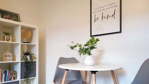 Una habitación moderna con una estantería blanca, una mesa redonda con dos sillas y una cita inspiradora enmarcada en la pared.