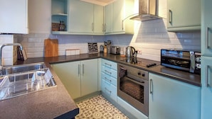 Una cocina con alacenas azul claro, un horno de acero inoxidable, un tostador y una cafetera.