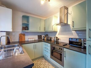 Eine Küche mit hellblauen Schränken, einem Edelstahlbackofen, einem Toaster und einer Kaffeemaschine.