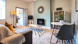 Una sala de estar moderna con un sofá, una mesa de centro, un televisor, una chimenea y una estantería.