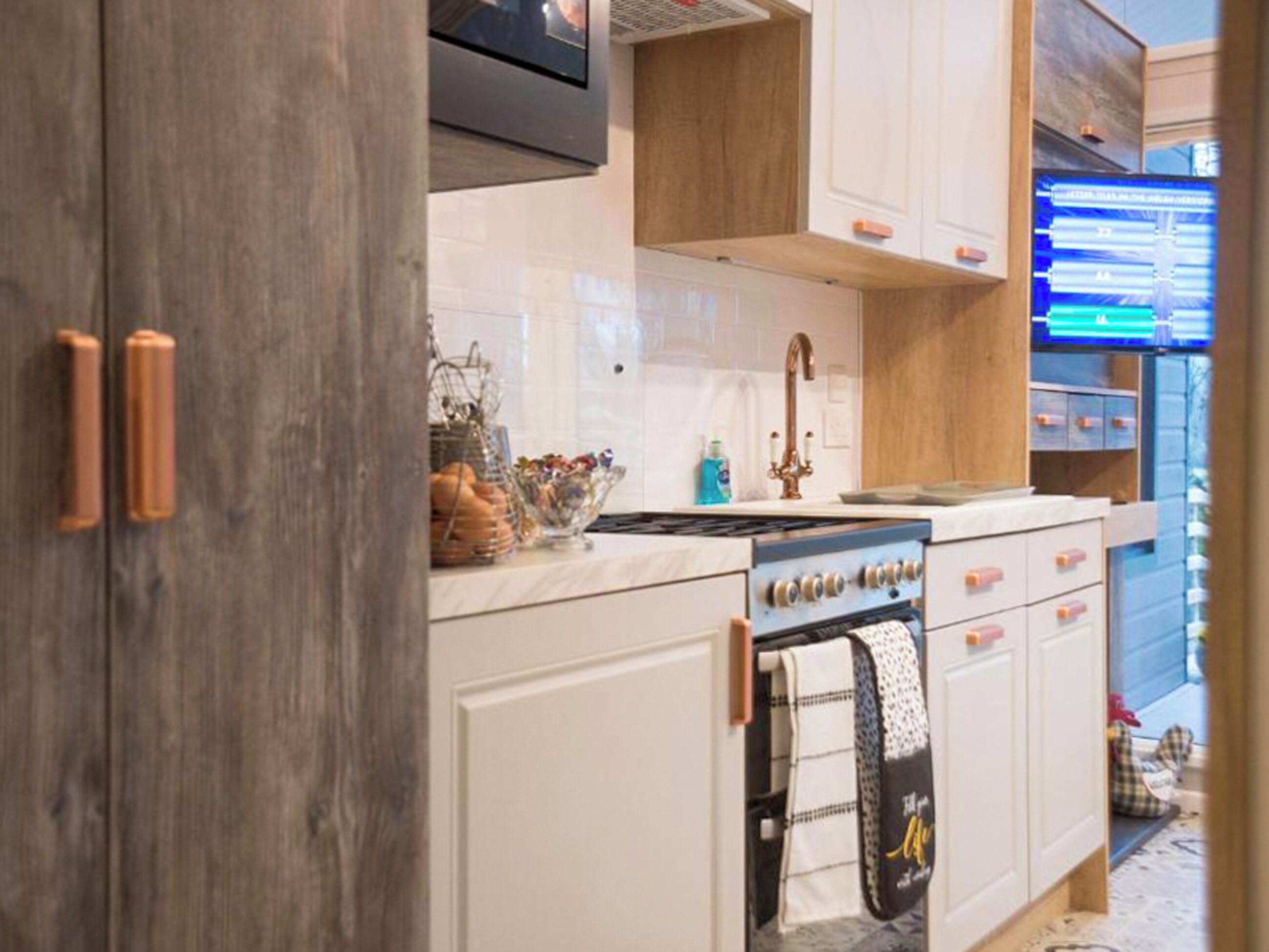 A kitchen with white cabinets, a stainless steel range hood, a built-in oven, and a wooden countertop.