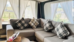 A modern living room with a sectional sofa, a small round table, and a wicker basket. - 2 bedroom accommodation in Rhayader and the Elan Valley (Rhayader and the Elan Valley)
