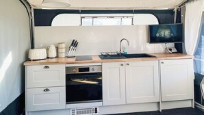 A compact kitchen with a sink, stove, and a television mounted on the wall. - 2 bedroom accommodation in Rhayader and the Elan Valley (Rhayader and the Elan Valley)