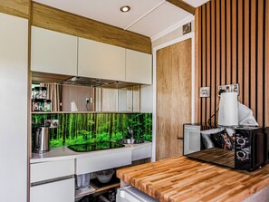 A modern kitchen with a wooden countertop, built-in cabinets, a stainless steel sink, and a wall-mounted speaker.