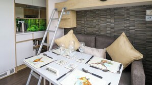 Interior modern d'un autocaravà amb zona de dinar, cuina i espai de sala d'estar.