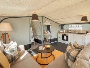 Ein kompaktes, gut beleachtetes Zelt mit einer Küchenzeile, einem Bett mit Moskitonetz und einer Sitzecke mit Tisch.