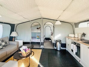 En kompakt autocamper indretning med et tekøkken, en sofa, et lille spisebord og køjeseng.