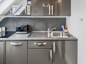 Een moderne keuken met een ingebouwde toaster, een spoelbak en roestvrijstalen kastjes.