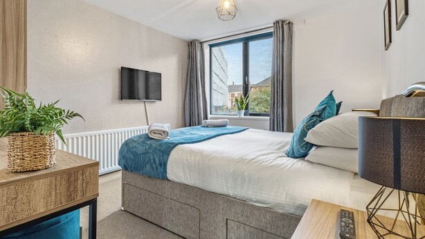 A modern hotel room with a bed, a desk, a television, and a window with curtains. - 2 bedroom accommodation in Jesmond (Jesmond)