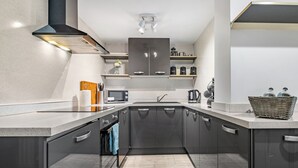 A modern kitchen with a central island, stainless steel appliances, and a built-in oven. - 2 bedroom accommodation in Jesmond (Jesmond)