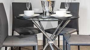 A modern dining table with a champagne bottle, two glasses, and white bowls and plates. - 2 bedroom accommodation in Jesmond (Jesmond)