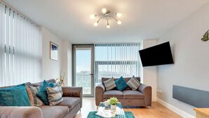 Ein modernes Wohnzimmer mit zwei Sofas, einem Couchtisch und einem an der Wand befestigten Fernseher.