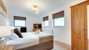 Ein modernes Schlafzimmer mit Bett, Fernseher, Kleiderschrank und Deckenleuchte.