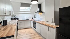 Eine moderne Küche mit Oberlichter, Holz Arbeitsplatten und einem schwarzen Kühlschrank.