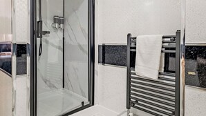 A modern bathroom with a glass-enclosed shower, a black towel rack, and a marble-tiled wall. - 2 bedroom accommodation in Tyne and Wear (Tyne and Wear)