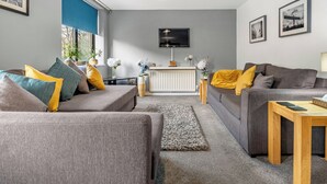 A modern living room with two sofas, a coffee table, and a TV mounted on the wall. - 2 bedroom accommodation in Tyne and Wear (Tyne and Wear)