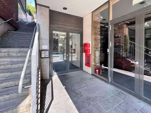 A modern building entrance with a glass door, a fire extinguisher, and a stairway. - 2 bedroom accommodation in Newcastle Upon Tyne (Newcastle Upon Tyne)