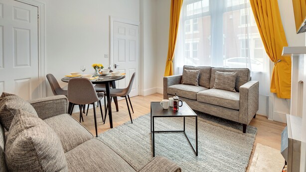 En moderne stue med sofa, sofabord og spiseplads.