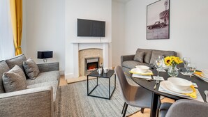 En moderne stue med pejs, spisebord til fire personer og en sofa.