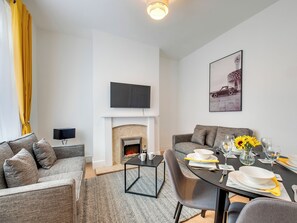 A modern living room with a fireplace, a dining table set for four, and a sofa. - 3 bedroom accommodation in Newcastle Upon Tyne (Newcastle Upon Tyne)