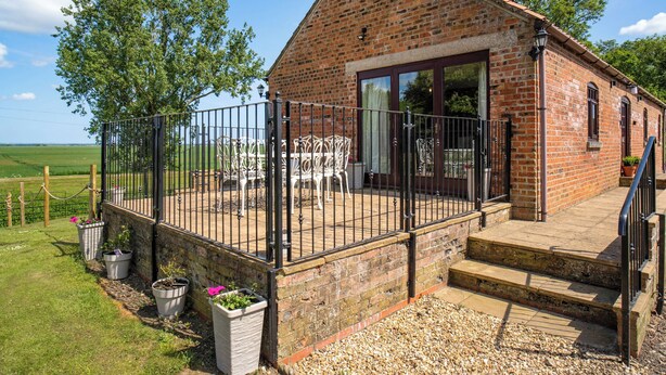 A brick house with a patio, outdoor seating, and a gravel pathway.