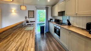 Una cocina moderna con suelo de madera, electrodomésticos de acero inoxidable y armarios de colores claros.