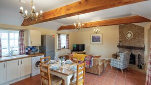 A spacious kitchen with a dining area, wooden beams, a fireplace, and a television. - The Coach House - UKC8853 (Blankney Fen)