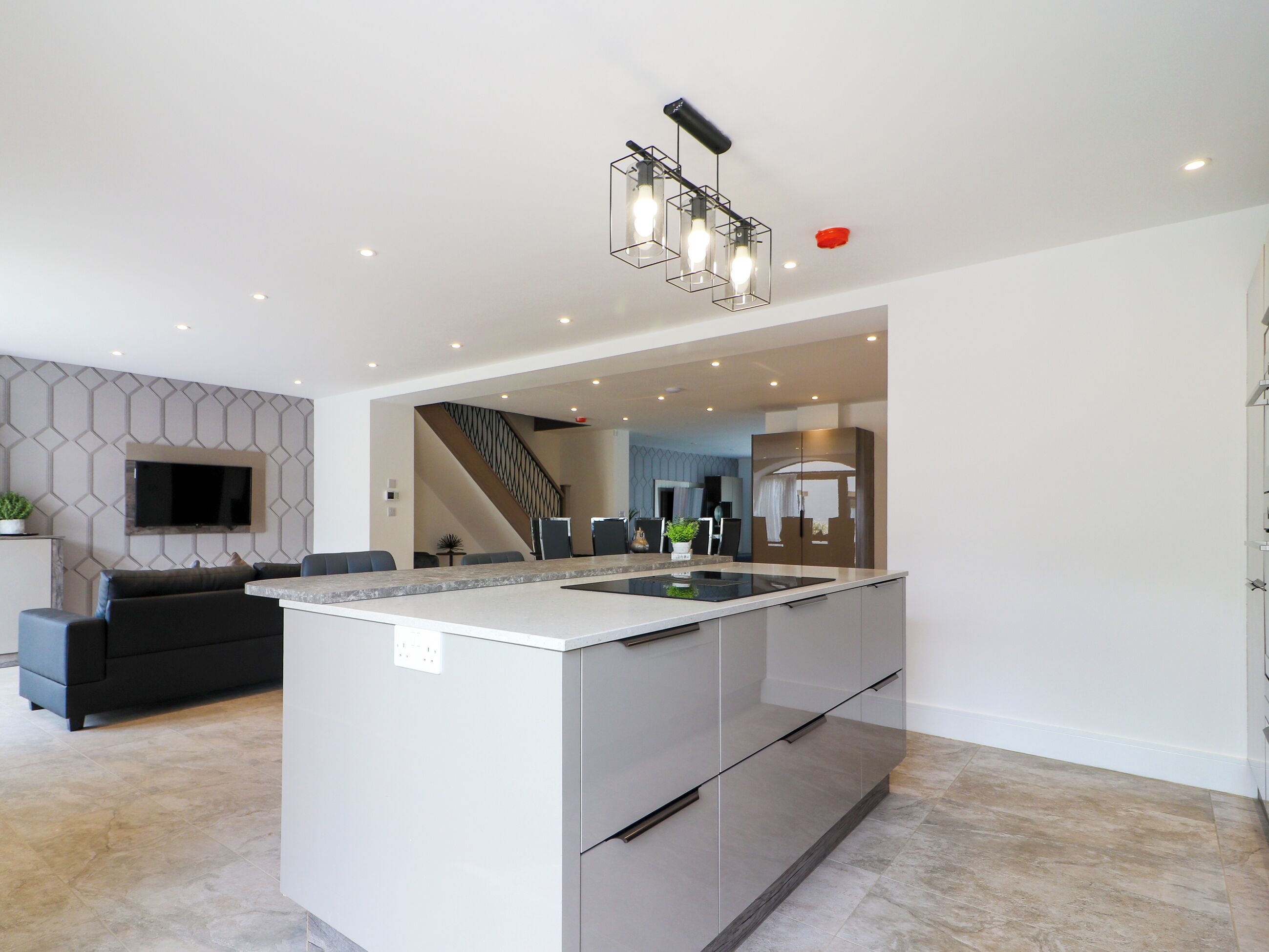 A modern kitchen with a central island, built-in appliances, and a staircase leading to an upper level.
