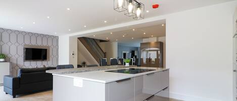 A modern kitchen with a central island, built-in appliances, and a staircase leading to an upper level.