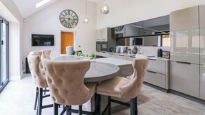 A modern kitchen with a central island, pendant lighting, and a large wall clock. - 15 Chivits - UKC8971 (Warkworth)