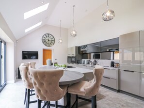 A modern kitchen with a central island, pendant lighting, and a large wall clock. - 15 Chivits - UKC8971 (Warkworth)