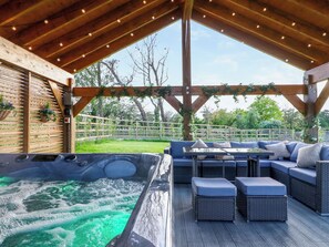 A wooden deck with a hot tub, outdoor seating, and a view of the surrounding greenery. - 15 Chivits - UKC8971 (Warkworth)