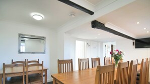 A dining area with a wooden table and chairs, a mirror on the wall, and a TV mounted on the wall. - 6 bedroom accommodation in Murton, near York (Murton, near York)