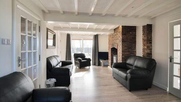 A spacious living room with a fireplace, leather sofas, and a television. - 6 bedroom accommodation in Murton, near York (Murton, near York)