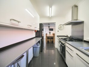 Eine moderne Küche mit Edelstahlgeräten, einem Essbereich mit Holztisch und -stühlen sowie einer an der Wand befestigten Uhr.