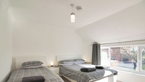 A modern bedroom with two beds, a window with curtains, and a ceiling light. - 6 bedroom accommodation in Murton, near York (Murton, near York)